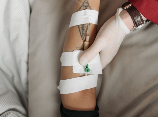 Close-up of a healthcare worker administering an IV to a patient's arm, focusing on the medical procedure.