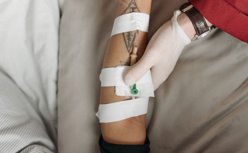 Close-up of a healthcare worker administering an IV to a patient's arm, focusing on the medical procedure.